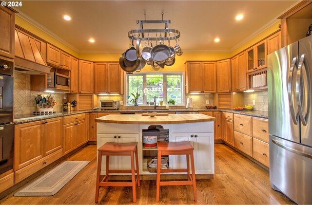 17130 Eastwood Ln, Brookings, OR 97415 - kitchen with appliances with stainless steel finishes, butcher block countertops, light wood-style floors, crown molding, and a kitchen island