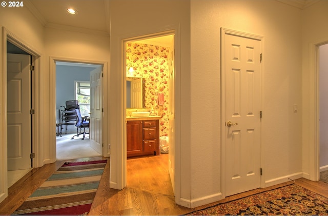 corridor featuring light wood-type flooring and ornamental molding