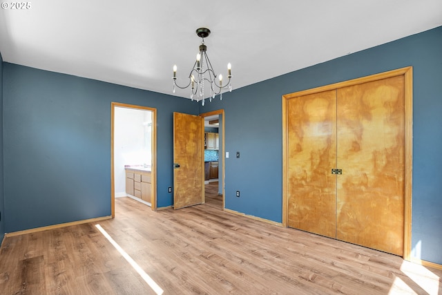 unfurnished bedroom featuring a chandelier, wood finished floors, baseboards, and a closet