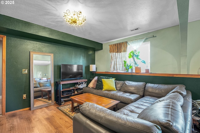 living area featuring wood finished floors, a textured ceiling, and a textured wall
