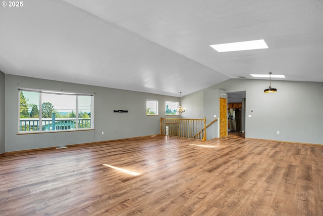 unfurnished living room with a skylight, vaulted ceiling, and wood finished floors