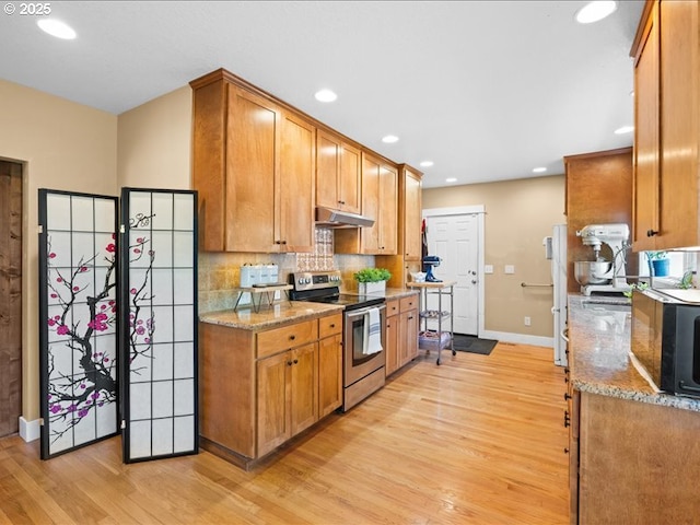 13283 NW Main St, Banks, OR 97106 - kitchen with electric stove, under cabinet range hood, baseboards, black microwave, and light wood-style flooring