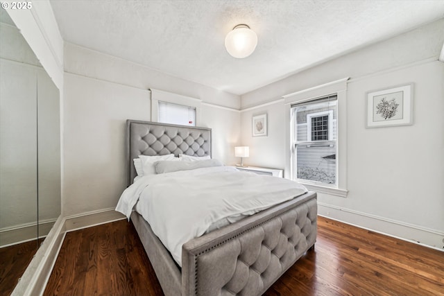 bedroom featuring a textured ceiling, dark wood-style flooring, and baseboards