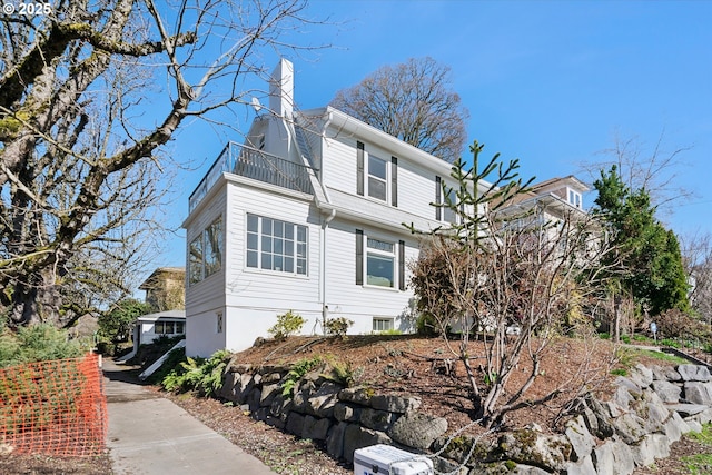 view of side of property featuring a chimney and a balcony