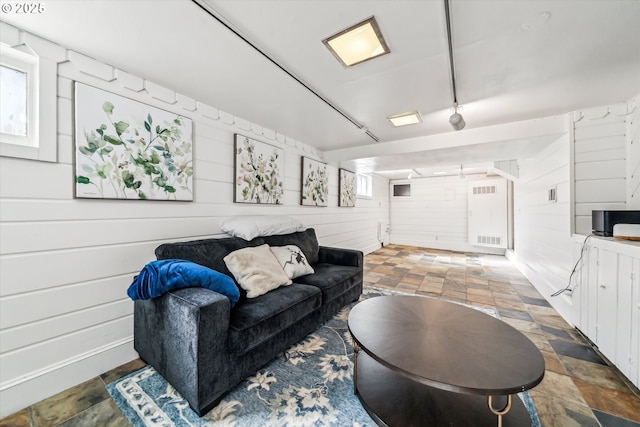 living area with stone finish flooring and wood walls