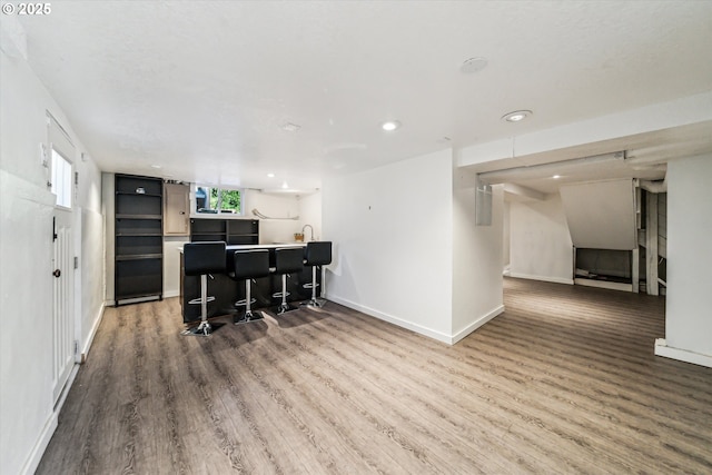 kitchen featuring baseboards, a breakfast bar area, wood finished floors, a peninsula, and open shelves