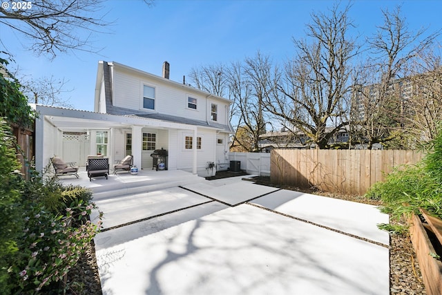 rear view of house with a patio area, a fenced backyard, a chimney, and central AC unit