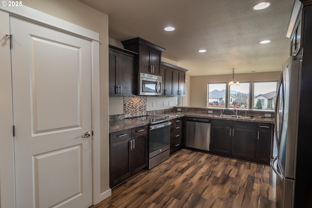 kitchen featuring dark wood-type flooring, a sink, dark brown cabinetry, appliances with stainless steel finishes, and decorative backsplash