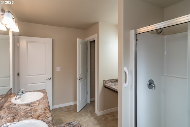 full bathroom with double vanity, a stall shower, and a sink