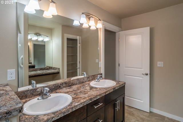 bathroom featuring a sink, baseboards, and double vanity