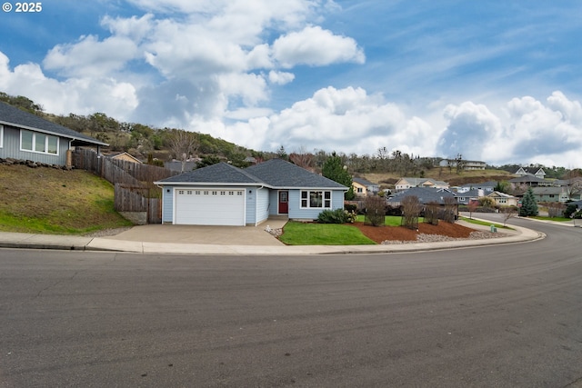 single story home featuring fence, an attached garage, concrete driveway, a front lawn, and a residential view