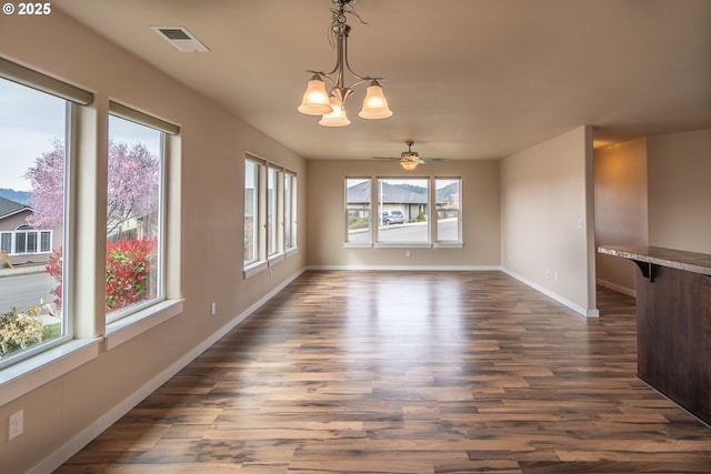 unfurnished dining area with visible vents, baseboards, dark wood-style floors, and ceiling fan with notable chandelier