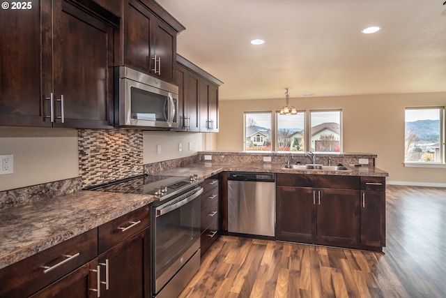 kitchen featuring a chandelier, dark brown cabinetry, a peninsula, stainless steel appliances, and a sink