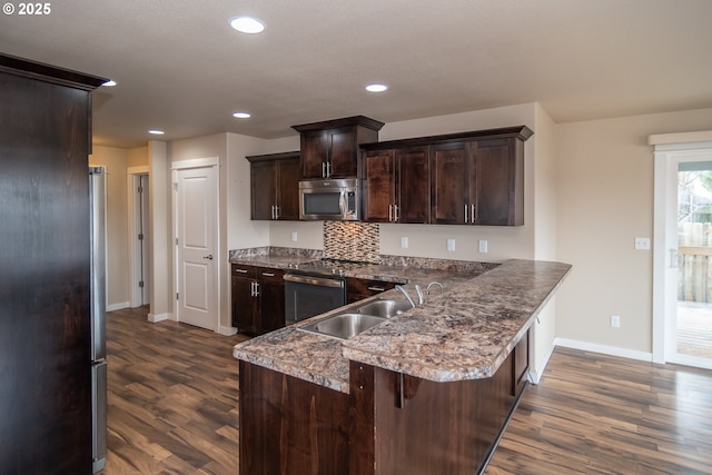 kitchen with a sink, stainless steel microwave, dark brown cabinets, and dark wood-style flooring