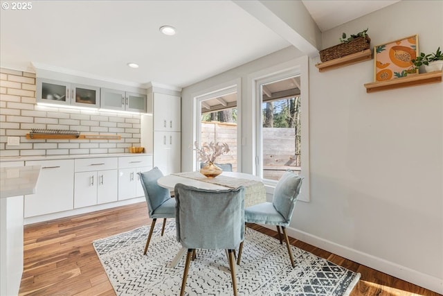 dining area with baseboards, wood finished floors, and recessed lighting