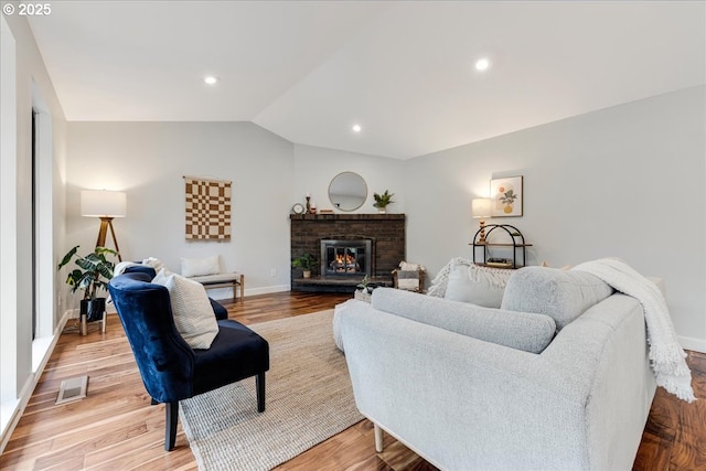 living room with lofted ceiling, light wood-style flooring, recessed lighting, visible vents, and a brick fireplace