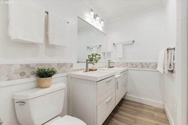 bathroom featuring vanity, ornamental molding, wood finished floors, and toilet