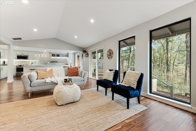 sitting room with lofted ceiling, visible vents, and wood finished floors