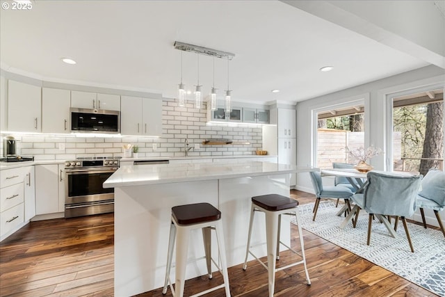 kitchen with appliances with stainless steel finishes, dark wood-type flooring, a center island, and white cabinets