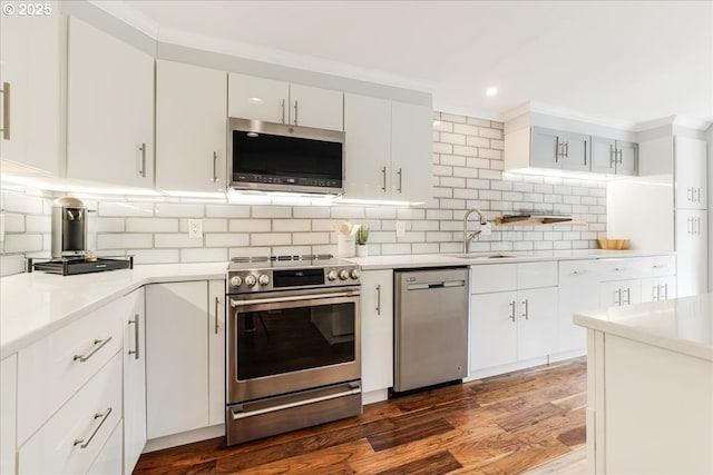 kitchen with dark wood-style flooring, light countertops, decorative backsplash, appliances with stainless steel finishes, and white cabinetry