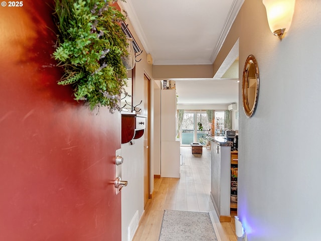 hall with visible vents, light wood-style flooring, and ornamental molding