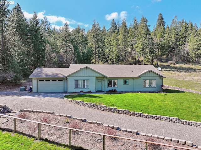 ranch-style home featuring a view of trees, driveway, board and batten siding, a front lawn, and a garage