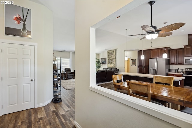 interior space with a towering ceiling, dark wood-style floors, baseboards, and ceiling fan