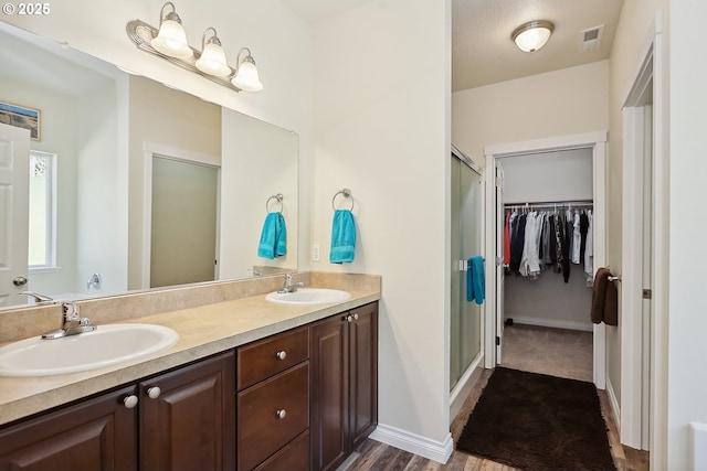 full bathroom featuring a shower stall, double vanity, visible vents, and a sink