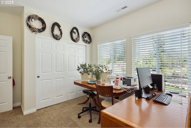 office area featuring visible vents, baseboards, and light carpet