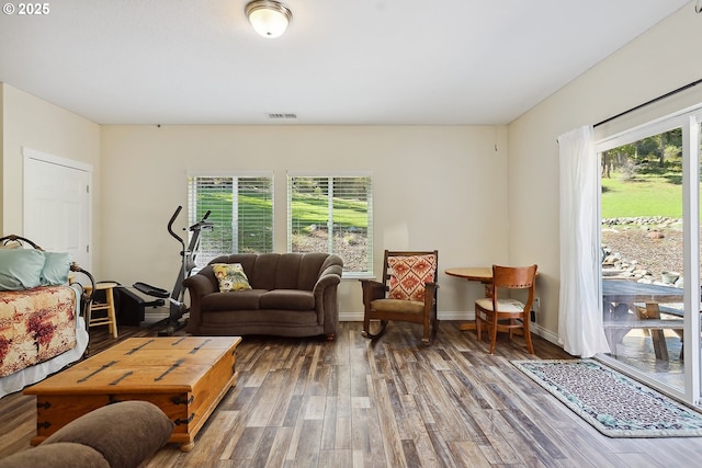 living area featuring wood finished floors, baseboards, visible vents, and a healthy amount of sunlight