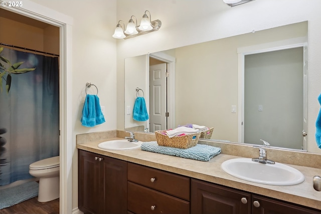 bathroom with double vanity, a sink, and toilet
