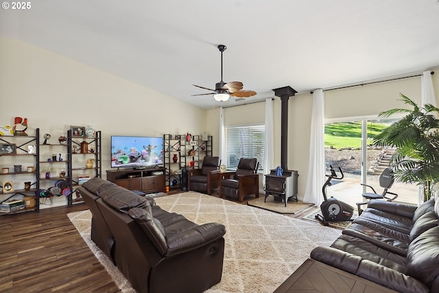 living area featuring wood finished floors, a wood stove, and a ceiling fan