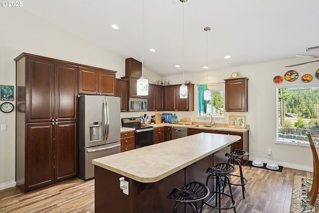 kitchen with light wood-style floors, appliances with stainless steel finishes, light countertops, a sink, and baseboards