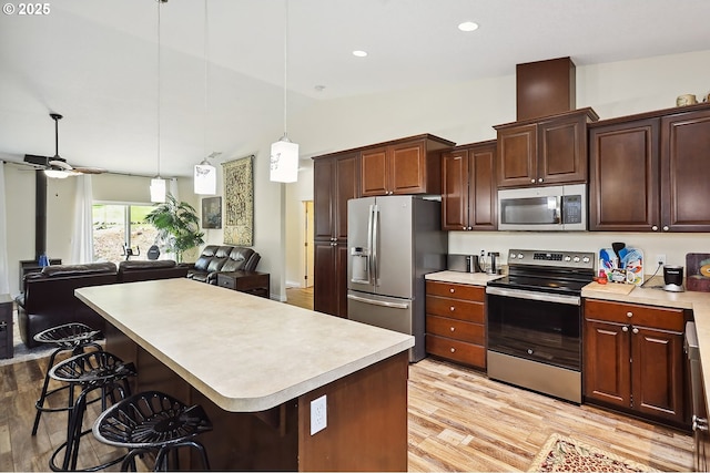 kitchen featuring open floor plan, light countertops, appliances with stainless steel finishes, and light wood-style floors