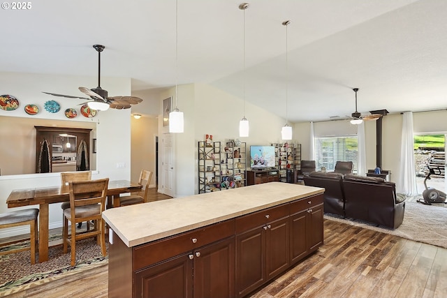 kitchen with vaulted ceiling, light countertops, a ceiling fan, and wood finished floors