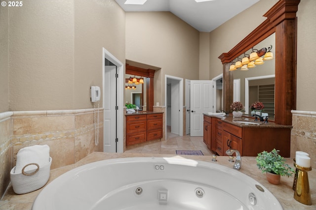1421 SE 79th Ct, Vancouver, WA 98664 - bathroom featuring a skylight, a tub with jets, vanity, a high ceiling, and wainscoting