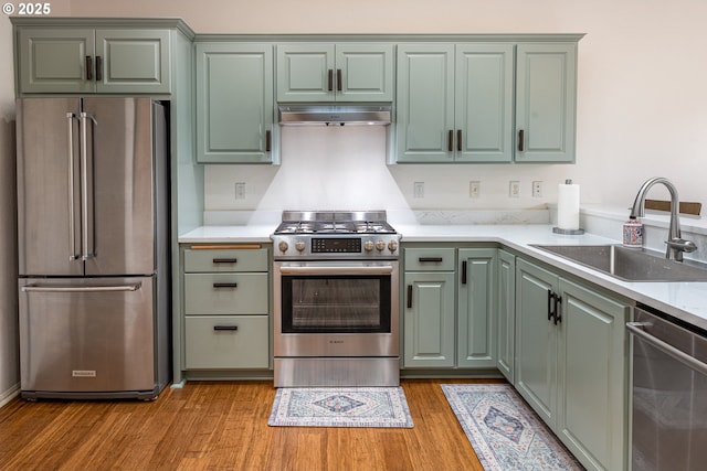 kitchen with sink, stainless steel appliances, light hardwood / wood-style floors, and green cabinetry