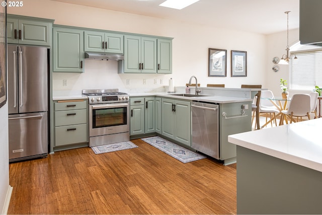 kitchen with sink, light hardwood / wood-style flooring, kitchen peninsula, pendant lighting, and stainless steel appliances