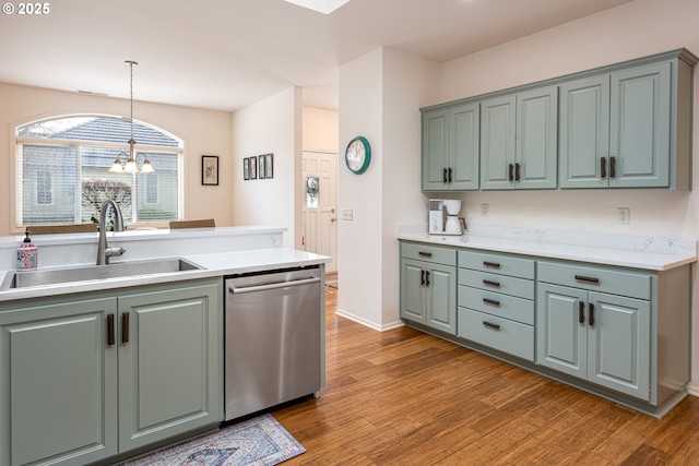 kitchen featuring sink, hanging light fixtures, stainless steel dishwasher, a notable chandelier, and hardwood / wood-style floors