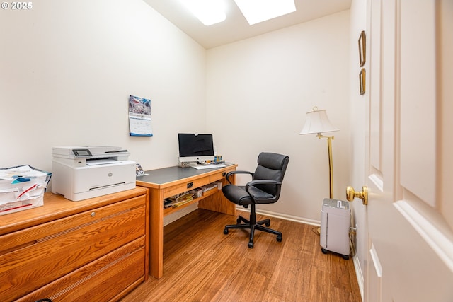 office with hardwood / wood-style flooring and a skylight