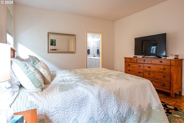 bedroom with hardwood / wood-style flooring, connected bathroom, and sink