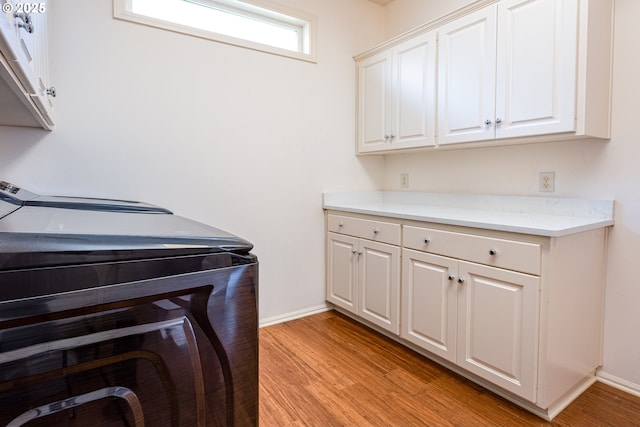 washroom with cabinets, light hardwood / wood-style floors, and washing machine and dryer