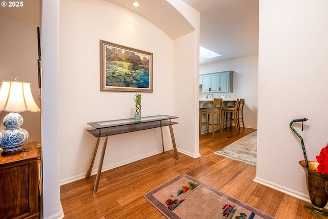 hallway with hardwood / wood-style flooring and a skylight