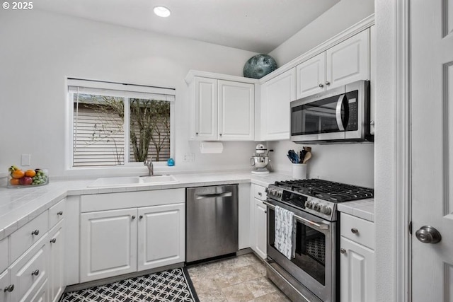 kitchen with white cabinets, appliances with stainless steel finishes, tile countertops, and a sink