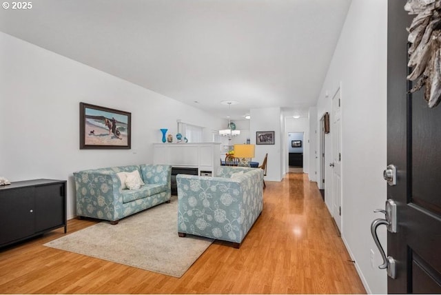 living area featuring baseboards, light wood-style floors, and a chandelier