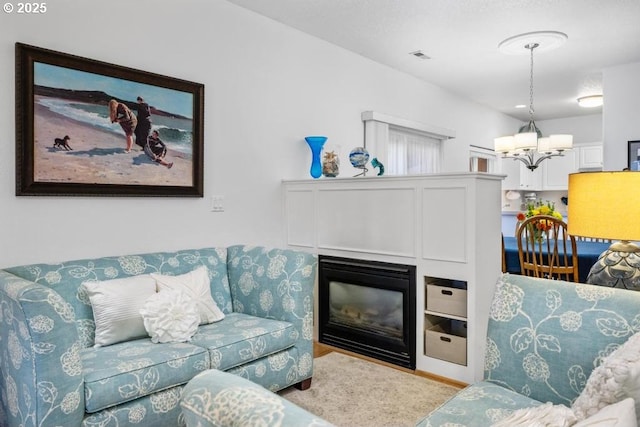 living area featuring a glass covered fireplace and a notable chandelier