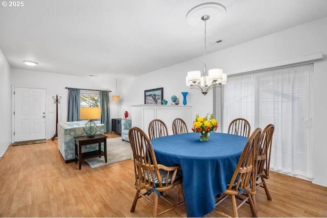 dining room featuring light wood-type flooring, an inviting chandelier, and visible vents