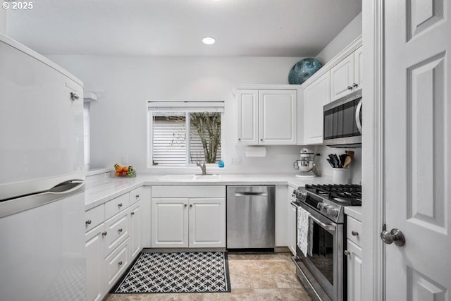 kitchen featuring recessed lighting, a sink, stainless steel appliances, light countertops, and white cabinetry