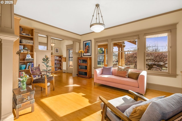 interior space featuring light wood-style floors, plenty of natural light, a fireplace, and decorative columns