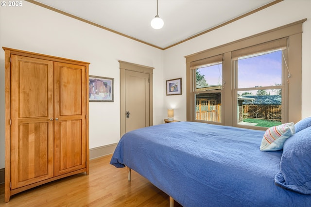 bedroom with crown molding, baseboards, and light wood-style flooring